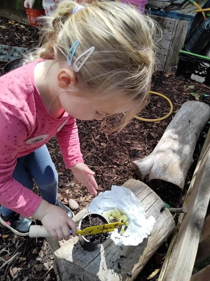 A child exploring soil and planting in the nursery garden
