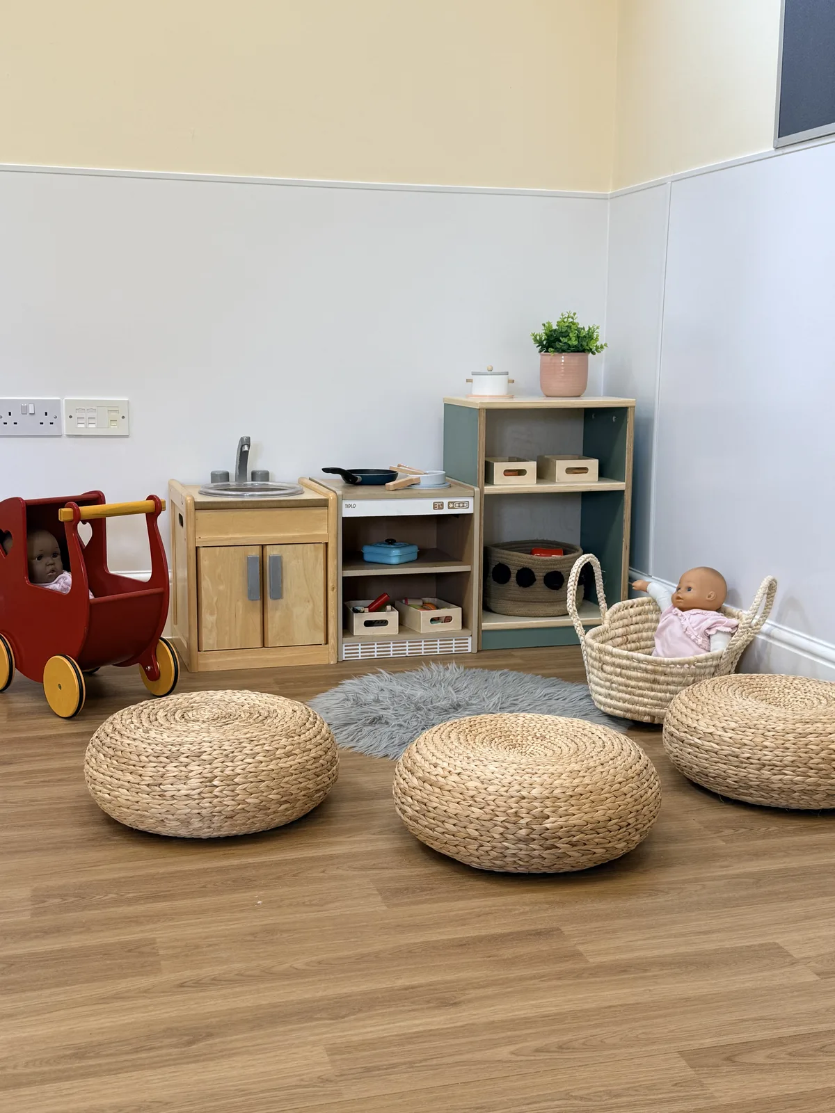 A cosy home corner with a play kitchen and woven seats at Limpley Stoke