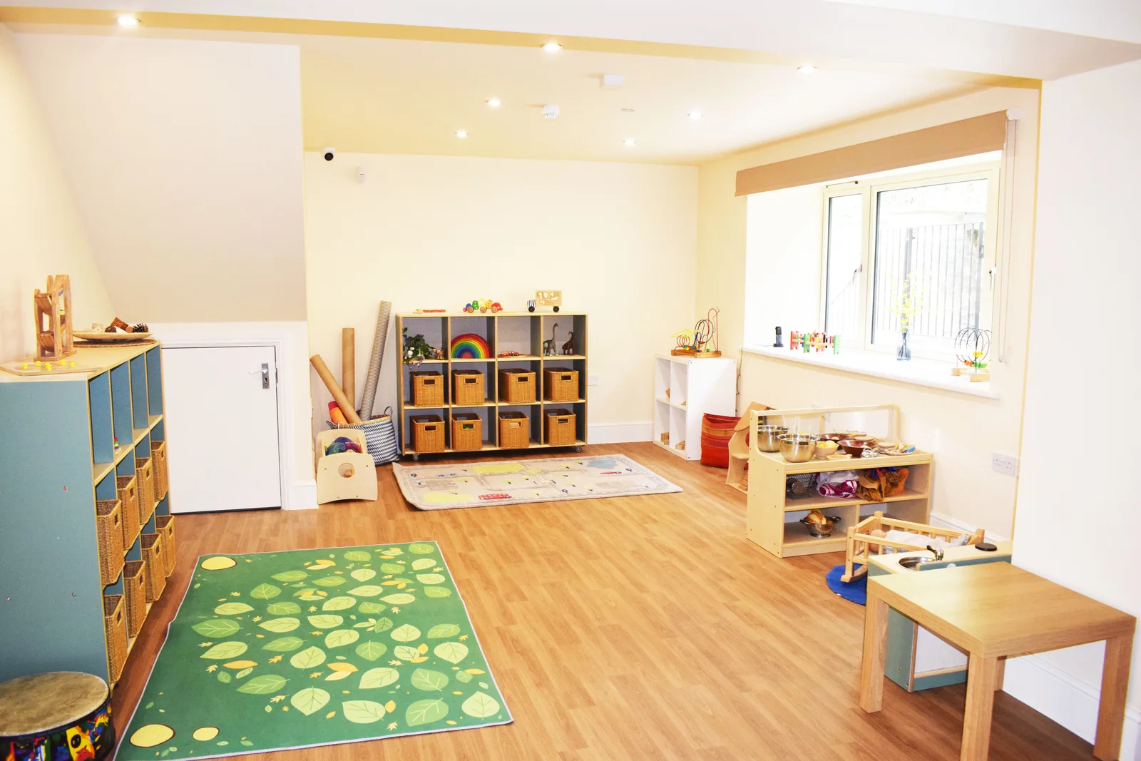 A bright playroom at Limpley Stoke with wooden toys and a leaf rug